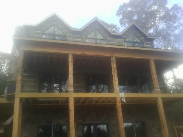 Dormers and porch framing on a large log home under construction — Roof Coating work by our crew in Wye Mills