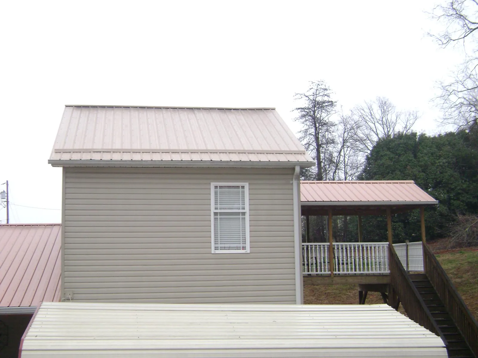 Tan metal roofs on a two story addition and attached porch, from a Roof Replacement job in Wye Mills