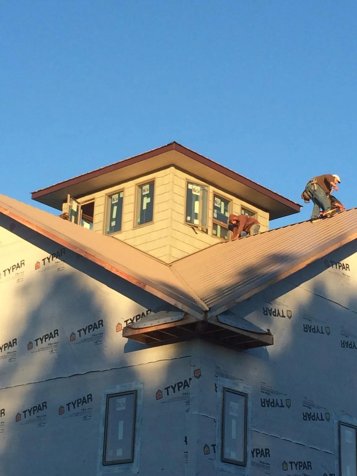 Roofers working around a rooftop cupola on a new metal roof at sunset — Roof Waterproofing in Wye Mills by Roofing Brothers